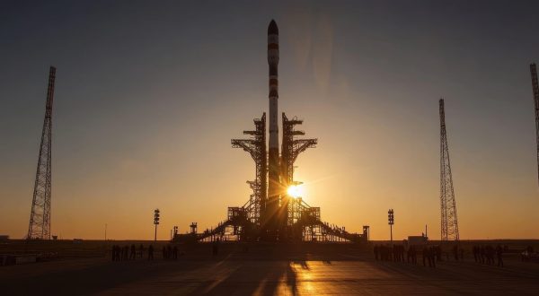 Rocket launch pad silhouetted against a sunset, showcasing a spacecraft and towers, highlighting space exploration technology.